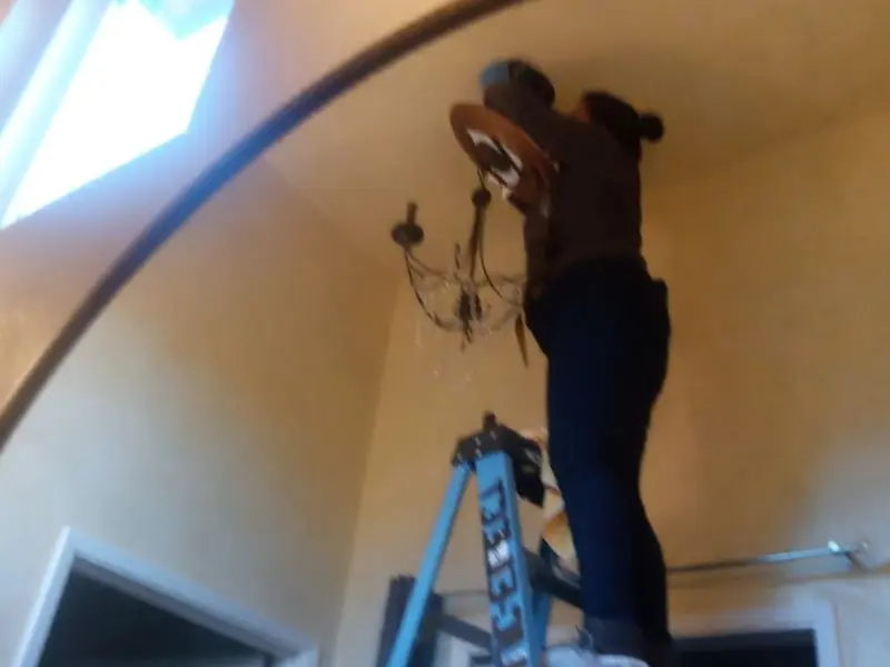Electrician installing a chandelier in a Wichita Falls residence